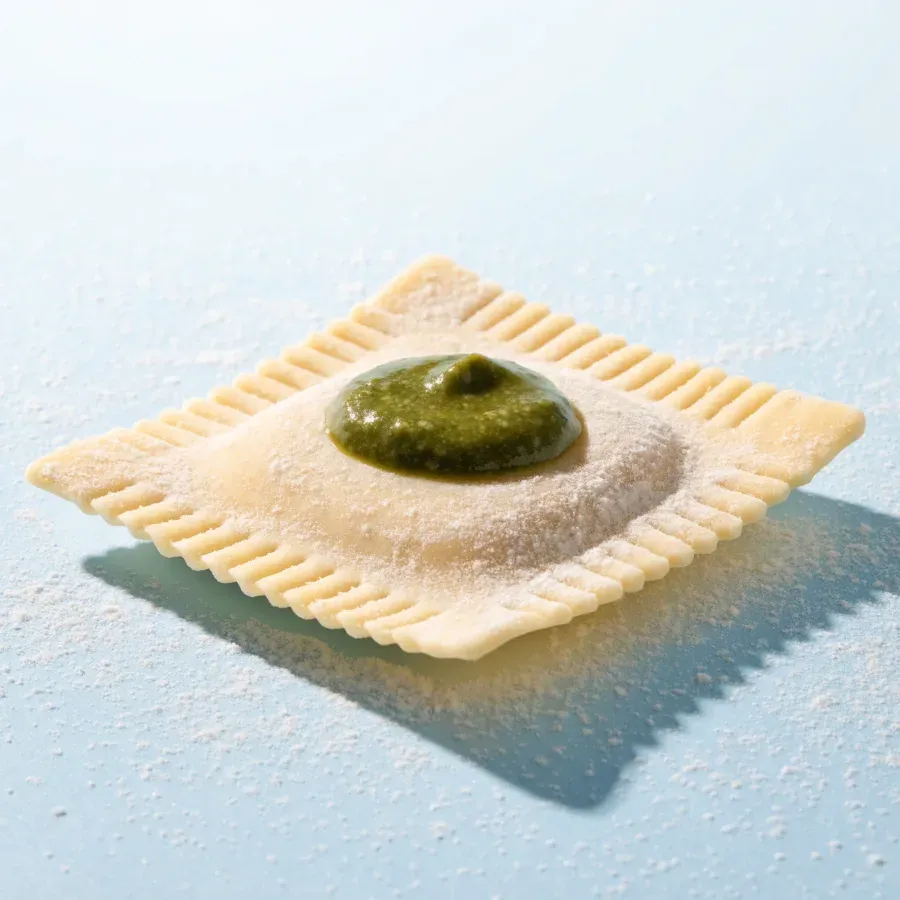 A fresh ravioli with a spoonful of glossy pesto on top