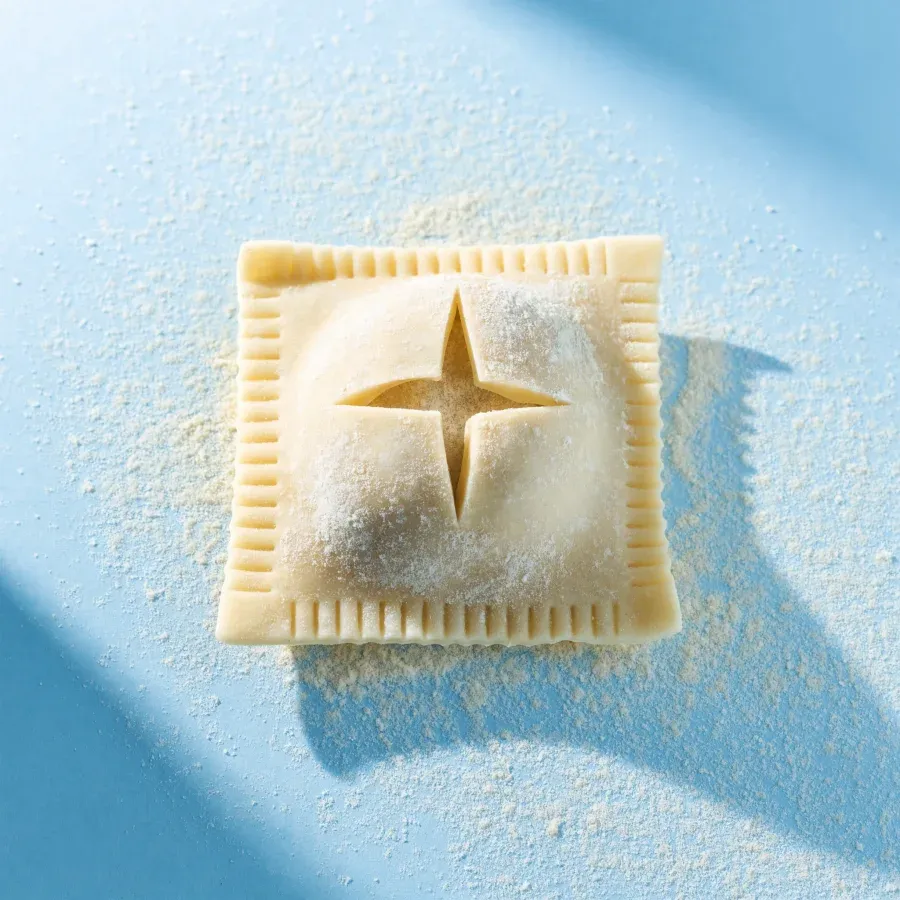 A fresh ravioli with a four-pointed spark carved into the dough
